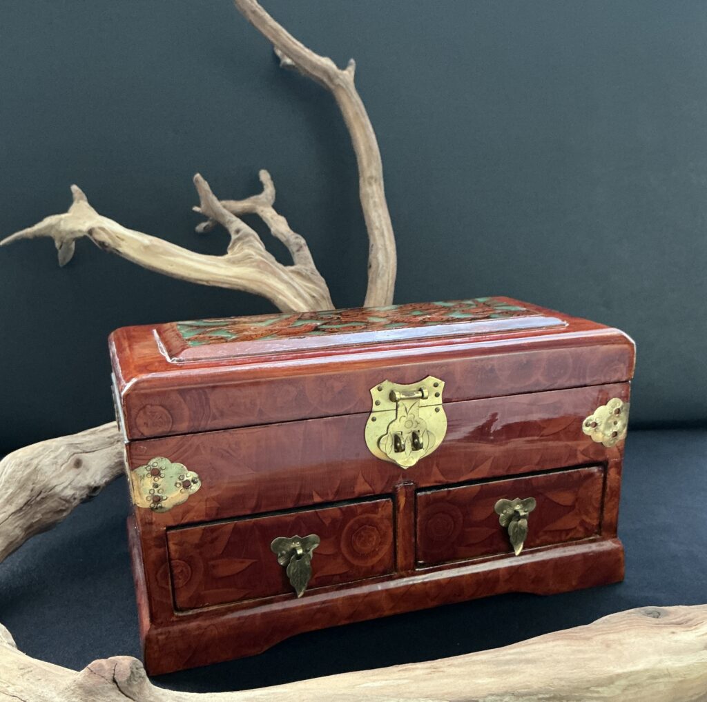 Rosewood 2 drawer high lacquor jewelry box near a branch of driftwood with a black background