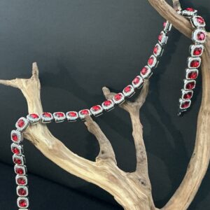 Silver tone red faceted crystal halo statement necklace draped over a driftwood branch with black background