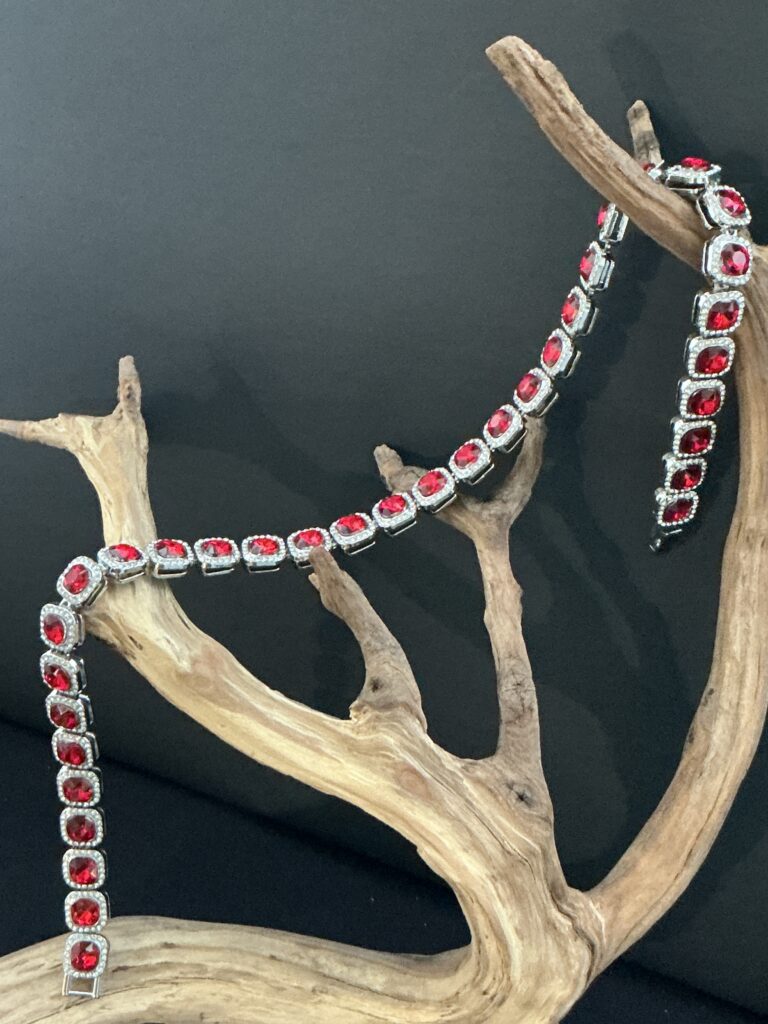 Silver tone red faceted crystal halo statement necklace draped over a driftwood branch with black background