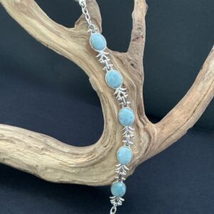 Larimar sterling 925 stamped bracelet hung on a driftwood branch with black background