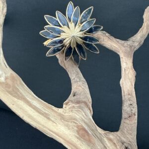 Vintage Corocraft Teal Glass Inlay Domed Flower Brooch Perched on a driftwood branch with blackbackground