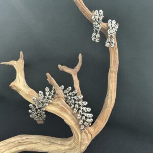 Tortolani bracelet and earring set hanging and draped on a driftwood branch with black backdrop