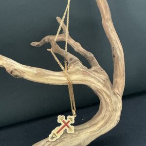 Cross pendant necklace draped on a driftwood branch with black background