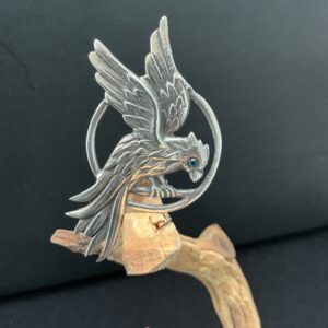 Bird brooch on a branch with black background