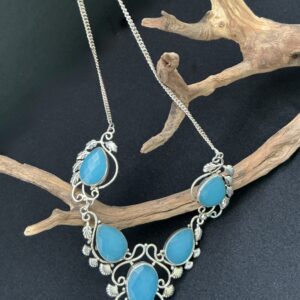 Artisan blue chalcedony 925 statement necklace draped over a droftwood branch with black background