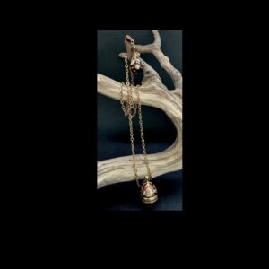Edgar Berebi necklace and pendant hung from a branch with black background