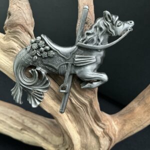 Hippocampus brooch perched on a driftwood branch with black background