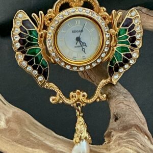 Edgar Berebi Wings of Time watch pendant brooch perched on a branch with black backdrop