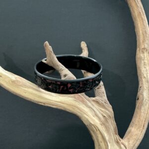 Red black carved cinnabar bangle perched on a branch with black background