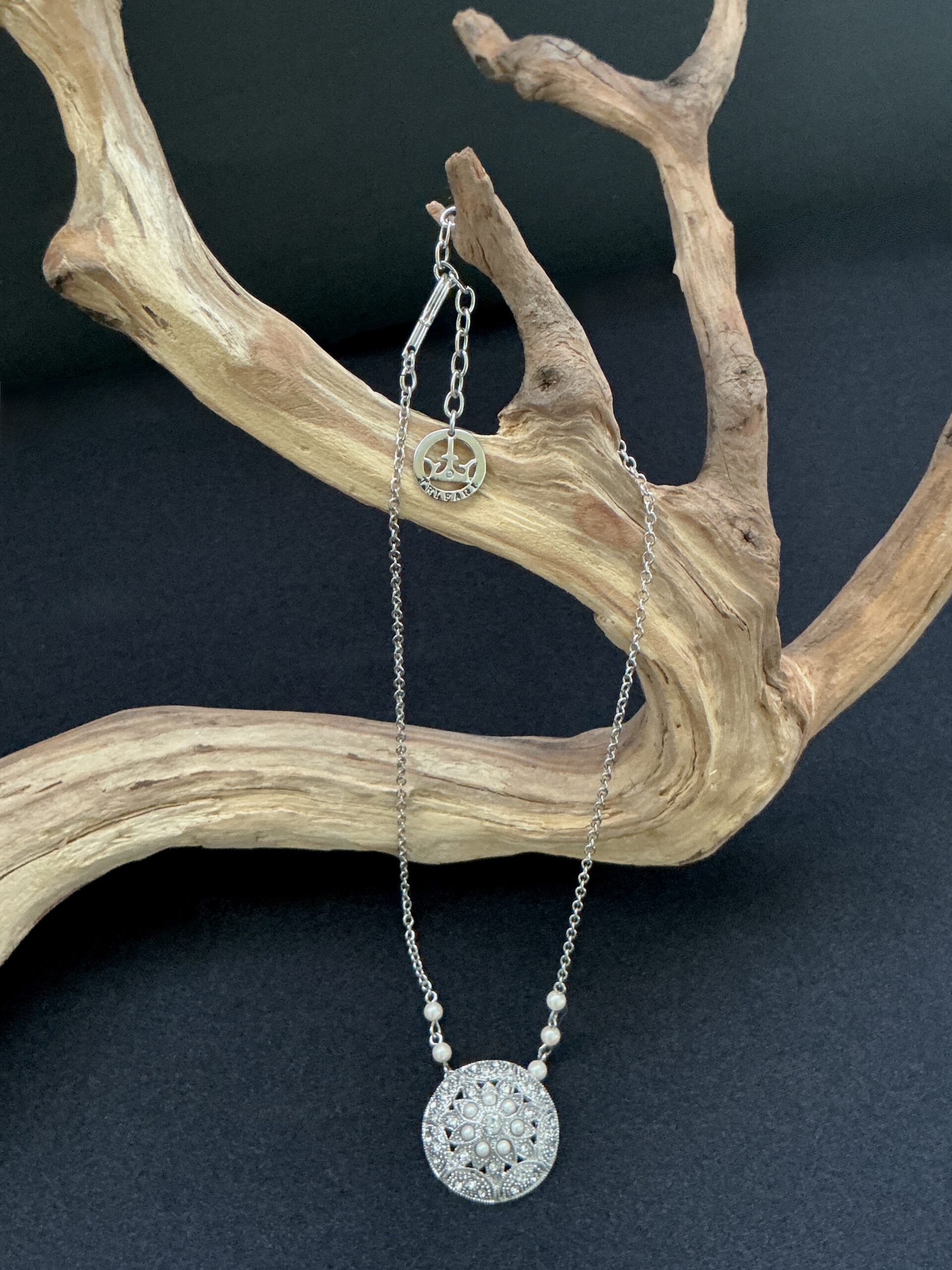 Trifari Silver tone pendant necklace hung on a branch with black background