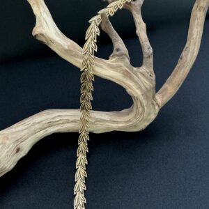 Boucher leaf design gold tone chocker draped open on a branch with a black background
