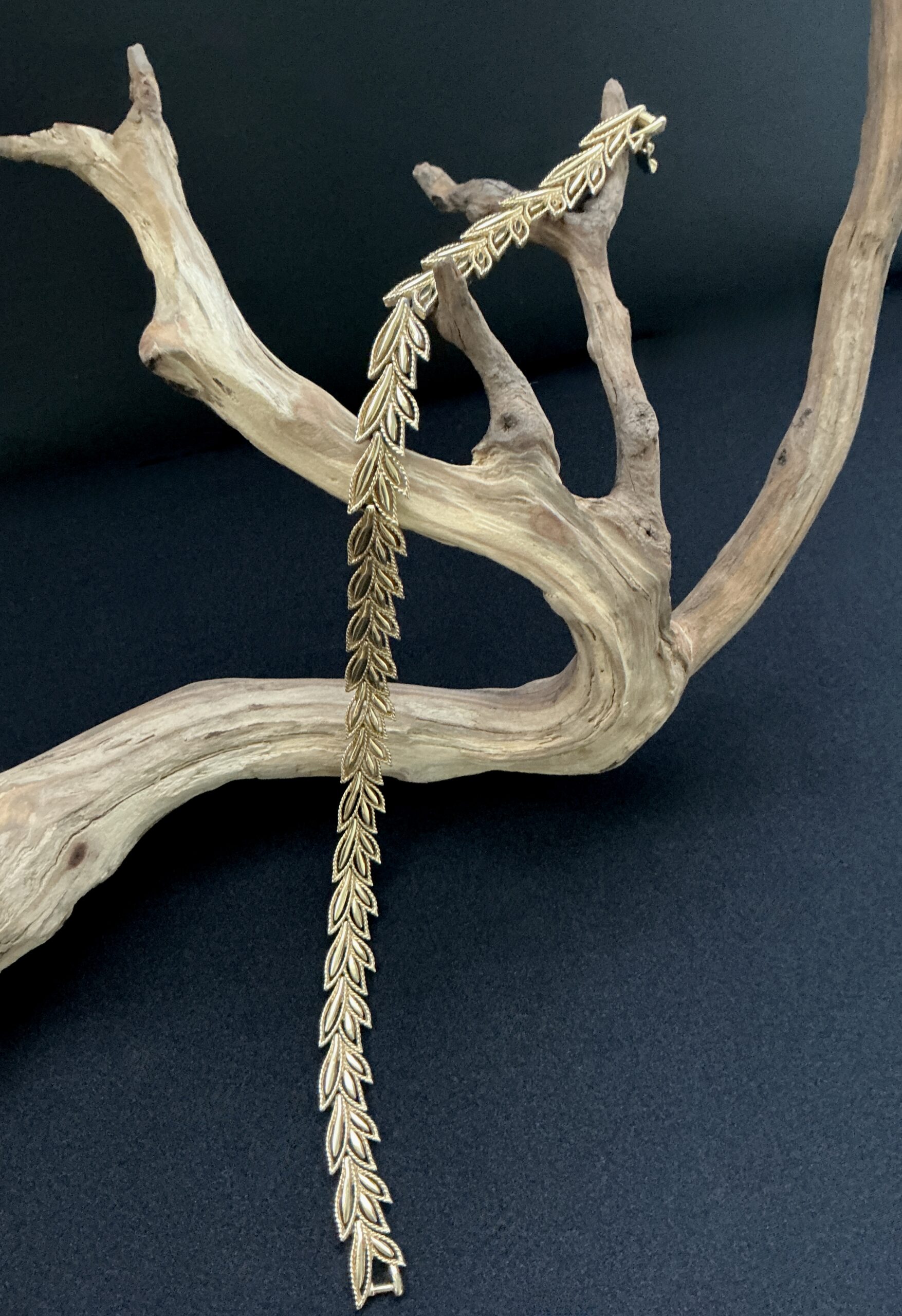 Boucher leaf design gold tone chocker draped open on a branch with a black background