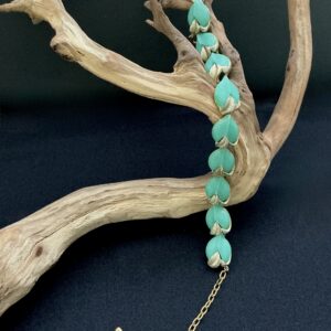 Mint green thermoset choker necklace draped over a branch with a black background