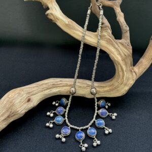 Lapis multi pendant necklace with bells draped on a branch with black background