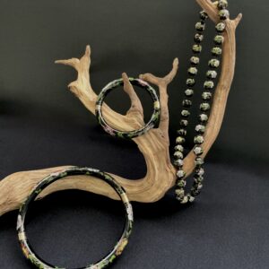 3 piece set of cloisonne vintage jewelry hung upon a branch with a black background