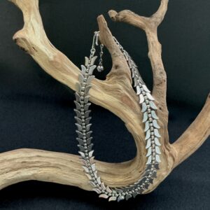 Trifari leaf silver tone choker draped on a branch with black background