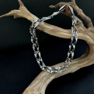 Silver square twist open link choker necklace draped over a branch with a black background