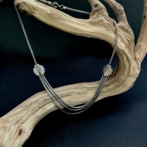 Double silver tone shell multi strand necklace hanging from a brach with a black background