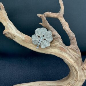 marcel boucher day to night four leaf clover brooch perched on a branch with a black background