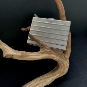 Vintage silver cigarette case perched on a branch with black background