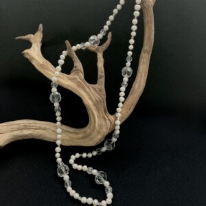 White pearl and clear crystal necklce draped on a branch with black background