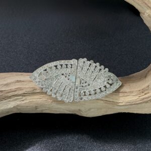 Silver tone rhinestone brooch perched on a branch with black background