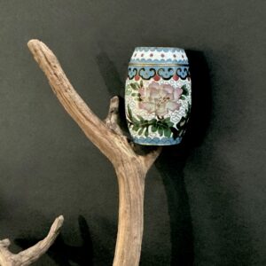 Cloisonne white trinket box perched on a branch with black background