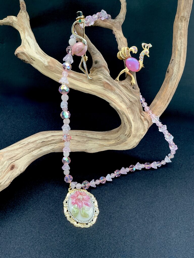 Curated wearable art: pink flamingo necklace and brooch on driftwood