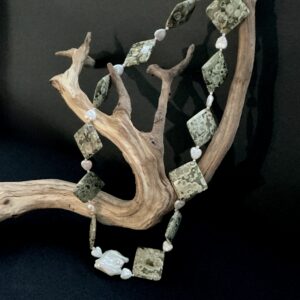 Green jasper and pearl necklace draped on driftwood