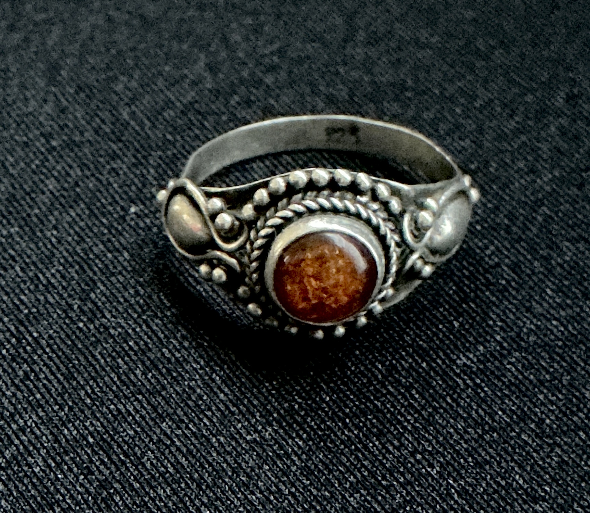 Close-up of an antique silver ring with a carnelian stone and intricate detailing.