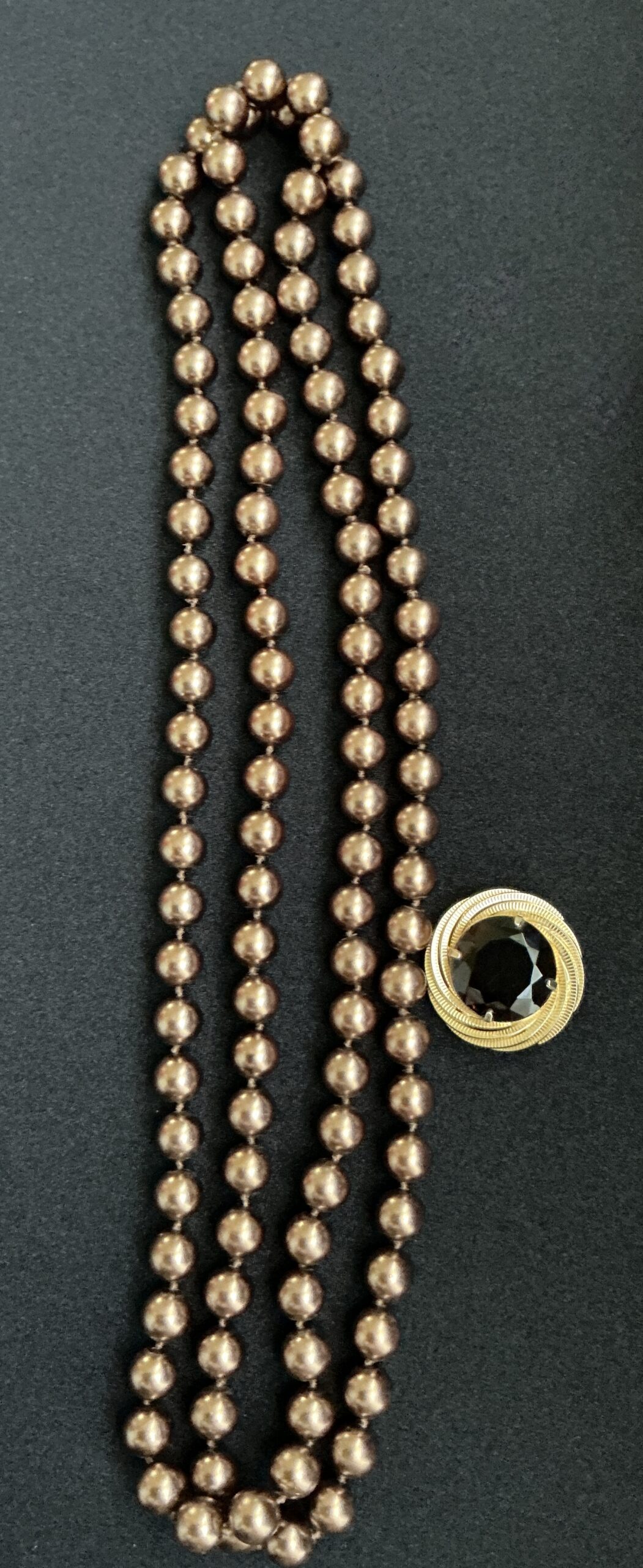Gold beaded necklace and a gold brooch with black stone