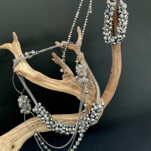 Silver crystal necklaces and bracelet draped on a wooden branch