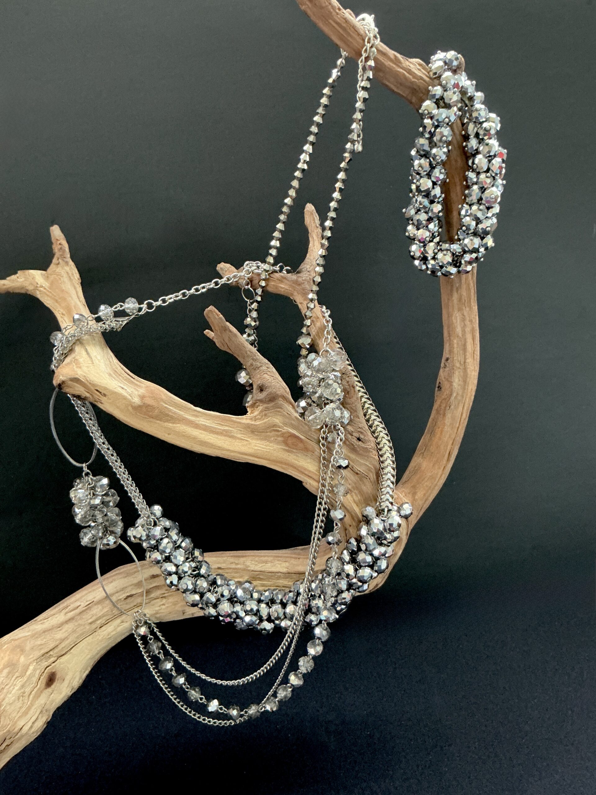 Silver crystal necklaces and bracelet draped on a wooden branch