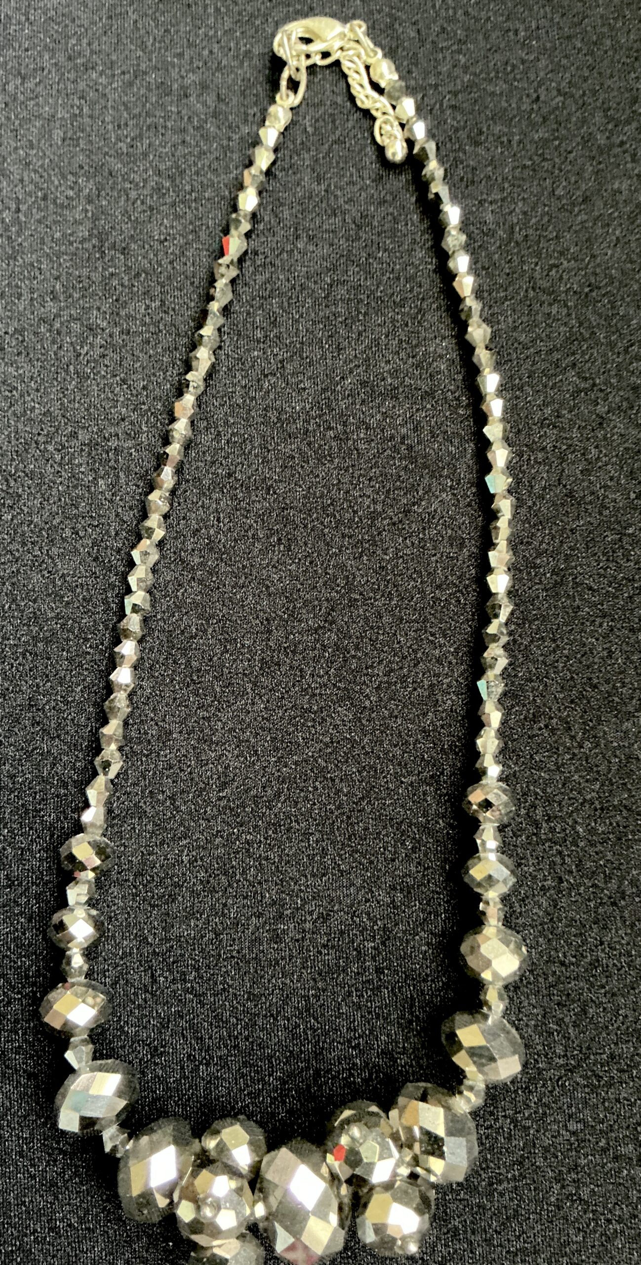 Silver faceted bead necklace with larger statement beads at the bottom