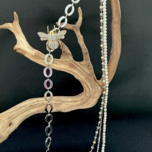 Gold and silver bee charm and multi strand necklace with pearls hung on a branch