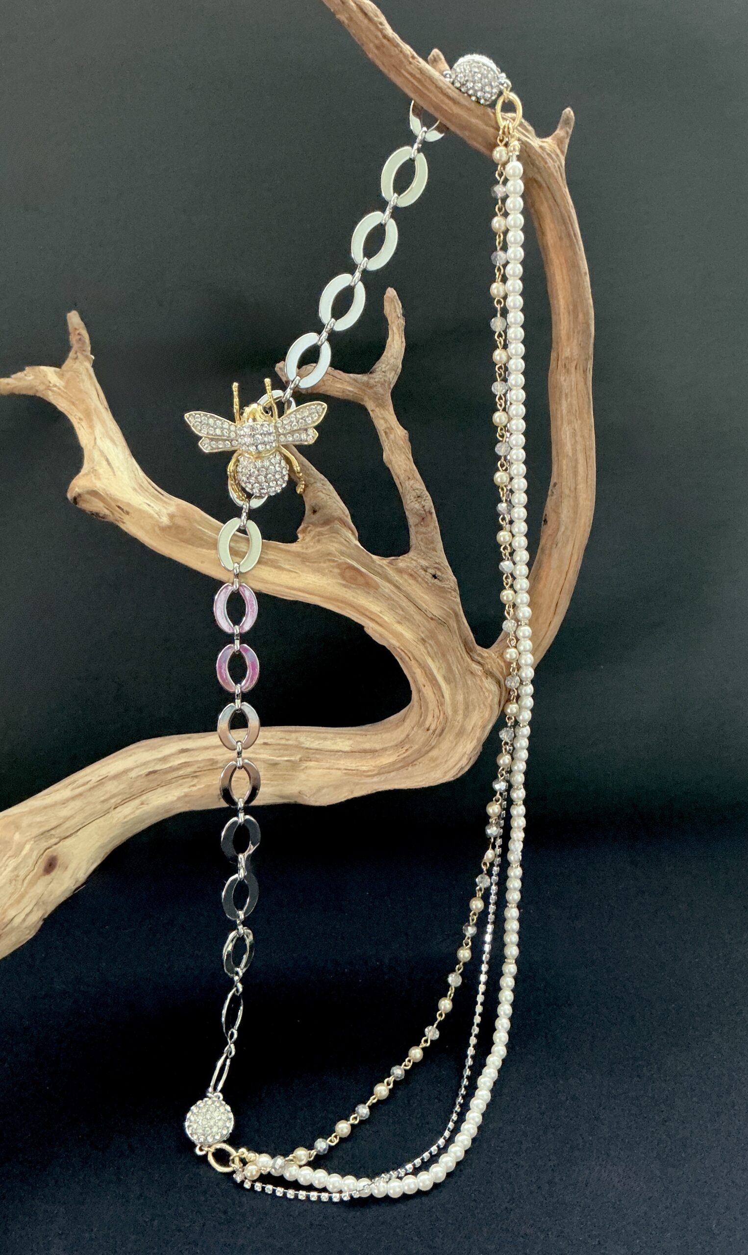 Gold and silver bee charm and multi strand necklace with pearls hung on a branch