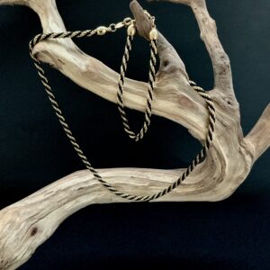 Gold and black twisted rope necklace and bracelet draped on driftwood