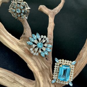 Three vintage brooches with blue rhinestones on a wooden branch