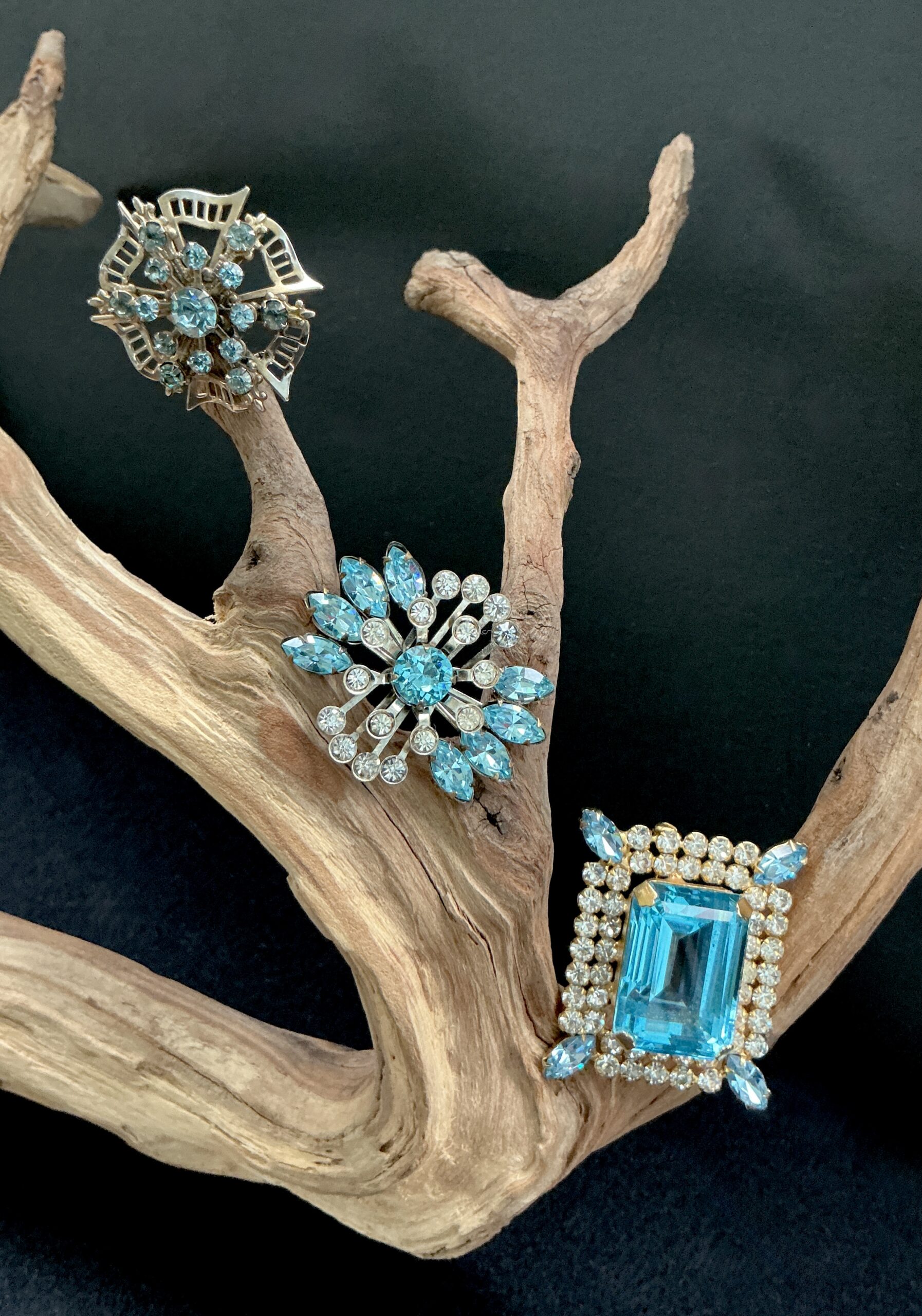 Three vintage brooches with blue rhinestones on a wooden branch